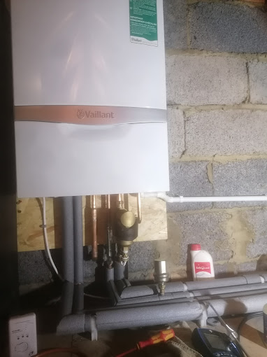 Vaillant boiler installation with insulated pipework mounted on a brick wall in a utility room or garage.