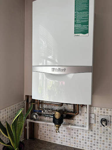 "Wall-mounted Vaillant boiler installation in a modern kitchen or utility room with tiled backsplash and exposed copper pipework.